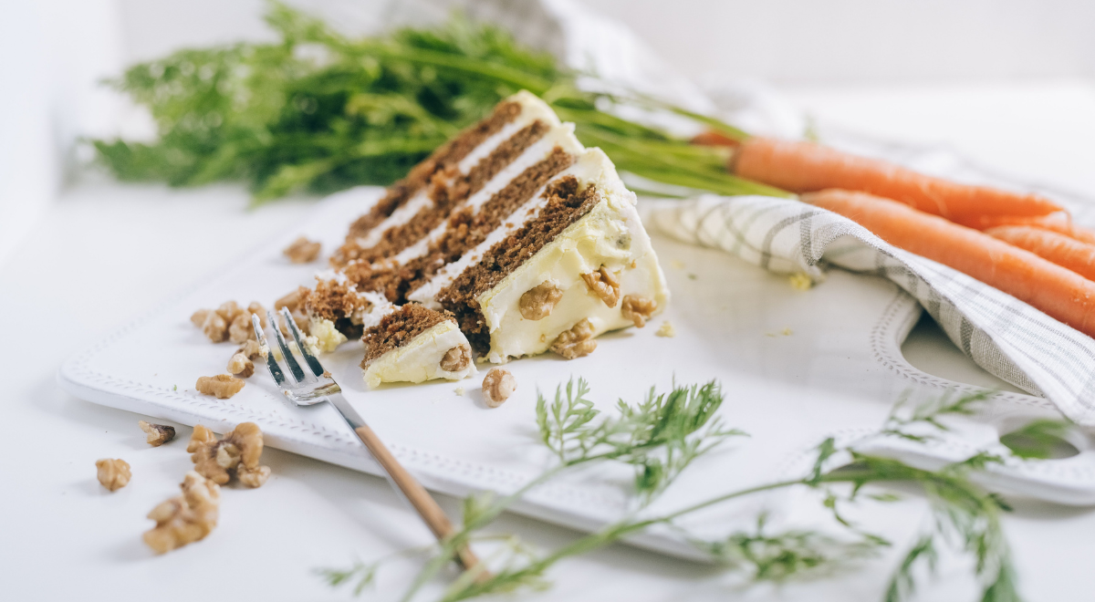close up of finished carrot cake with cream cheese frosting swirls and walnut pieces on top